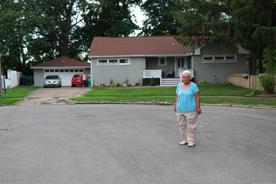 Luella Kenny standing in front of the house she left behind almost 40 years ago. Photo source: Nick Lippa/WBFO