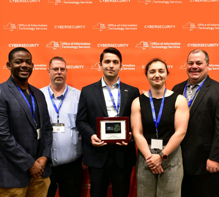 Arbina Camaj, fourth from right, was one of 19 state employees recognized as State Cybersecurity Champions for their significant contributions to support and enhance cybersecurity across New York State. The winners were honored at the 26th Annual New York State Cybersecurity Conference on June 4. From left to right are Stephen Addison, Joel Butler, Shawn Fodor, Camaj, and Ben McFarland.