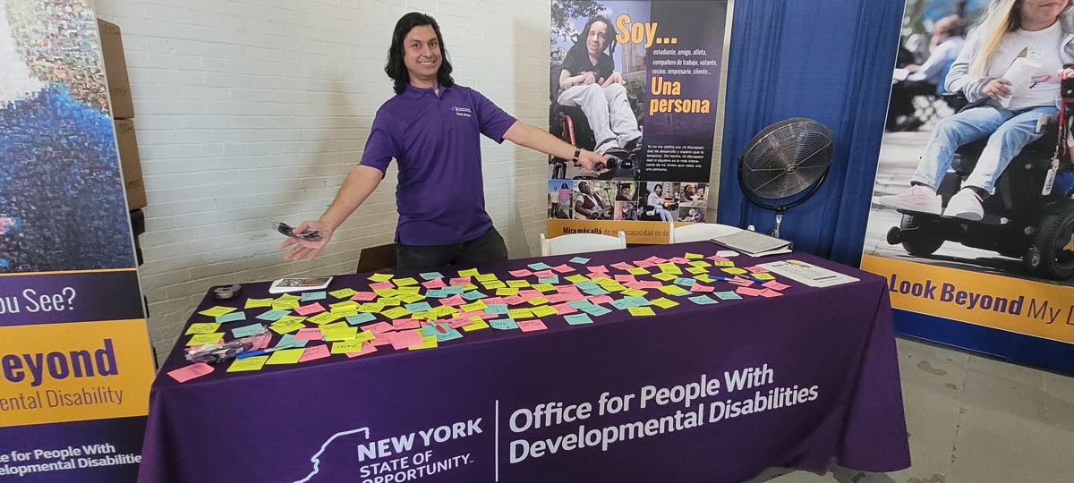 OPWDD PEF member Thomas Galla shares the Look Beyond project with 2023 State Fair attendees through a sticky note activity.