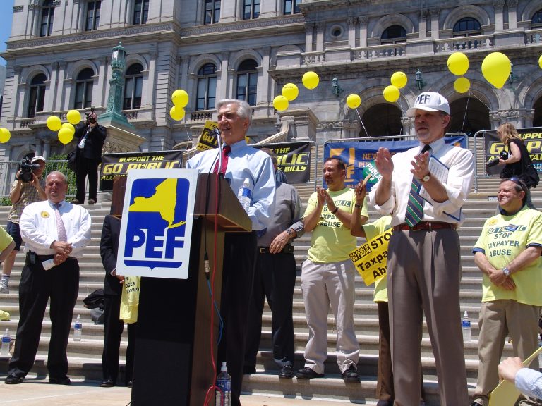 Roger Benson, in hat, participates in a “Go Public” rally at the State Capitol to call out the State’s use of private contractors.